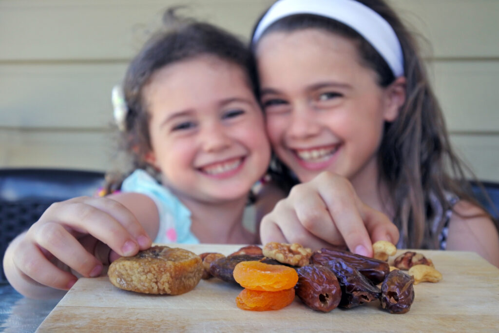 Girls enjoying dried fruits on Tu'bshvat - The Festival of Trees ©Shutterstock.com
